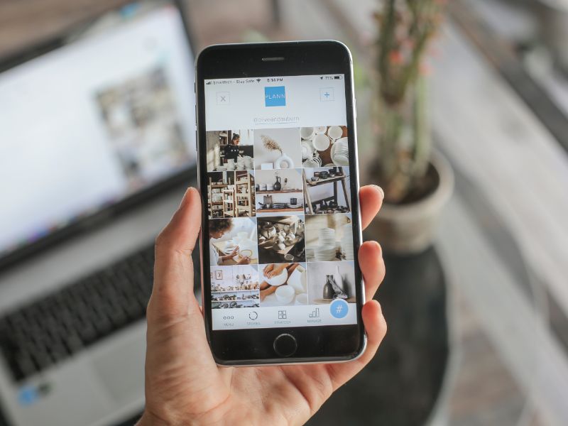 Hand holding a smartphone with an Etsy shop open, showing engagement with customer reviews and messages